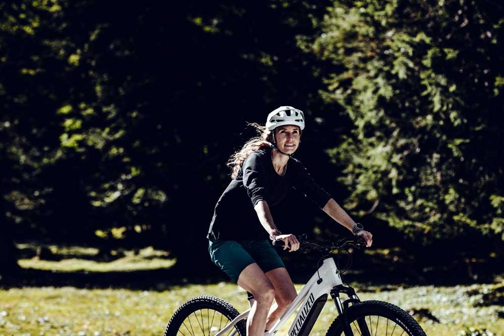 nainen pyöräilee kesäisessö maisemassa